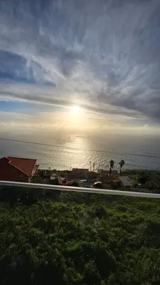 a road in front of the ocean with the sun in the sky at Majestic Seaview Villa in Fajã da Ovelha