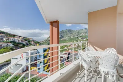 a balcony with white chairs and a view at Camara de Lobos Duplex Apartment by Holiday Rental Madeira in Câmara de Lobos