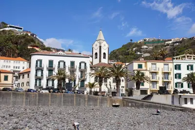 a group of buildings on a beach with a clock tower at Camara de Lobos Duplex Apartment by Holiday Rental Madeira in Câmara de Lobos