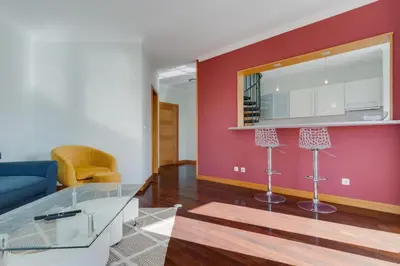 a living room with a blue couch and a red wall at Camara de Lobos Duplex Apartment by Holiday Rental Madeira in Câmara de Lobos