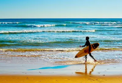 a man walking on the beach with a surfboard at Villa Back Loop in Sagres