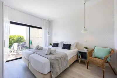 a bedroom with a bed and a chair and a window at Villa Back Loop in Sagres