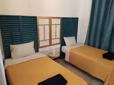 two beds in a room with blue shuttered windows at Bus Stop House 84 in Funchal