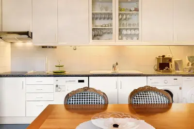 a kitchen with white cabinets and a wooden table at Bela Sao Tiago 36 in Funchal