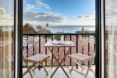 a table and chairs on a balcony with a view of the ocean at Bela Sao Tiago 36 in Funchal