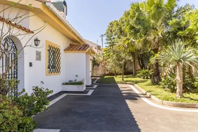 a driveway in front of a house with palm trees at Villa Echium T2 in Caniço