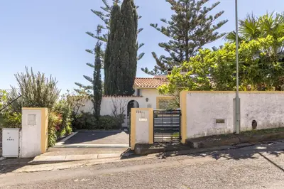 a white house with a gate and trees at Villa Echium T2 in Caniço