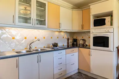 a kitchen with white cabinets and white appliances at Villa Echium T1 in Caniço