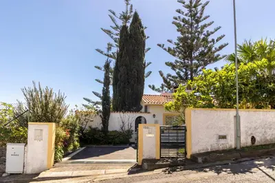 a house with a gate and a tree at Villa Echium T1 in Caniço