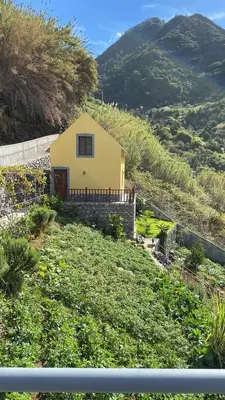 a yellow house on the side of a hill at casa caminho da praia in Porto da Cruz