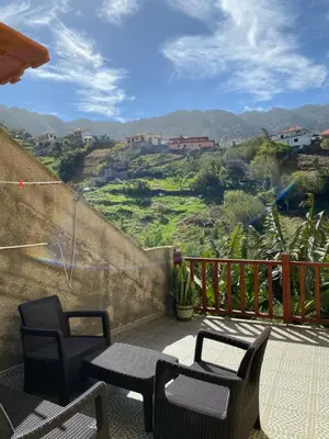 a balcony with chairs and tables and a view of a hill at casa caminho da praia in Porto da Cruz