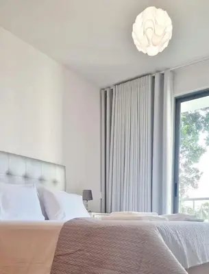 a white bedroom with a large bed and a window at Ocean Pearl Apartment M in Funchal