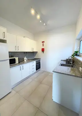 a large kitchen with white cabinets and a sink at Casa Sagres T2 - 3 minutos a pé Praia da Mareta in Sagres