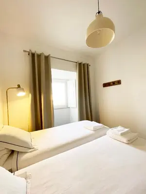 two beds in a room with a window at Casa Sagres T2 - 3 minutos a pé Praia da Mareta in Sagres