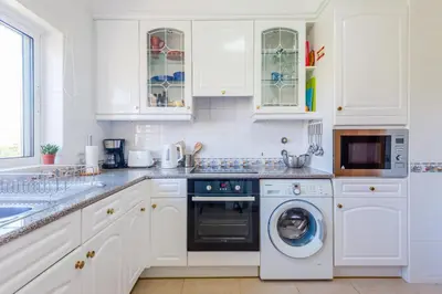 a white kitchen with white cabinets and a dishwasher at Fairviews Village - Boavista Resort in Lagos in Lagos