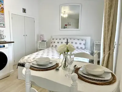 a white dining room table with plates and flowers on it at Modern Minimalist Studio with Essential Comfort in Funchal