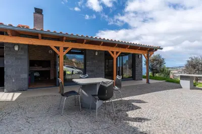 a patio with a table and chairs in front of a building at Gran Horizonte House by Holiday Rental Madeira in Ribeira Brava