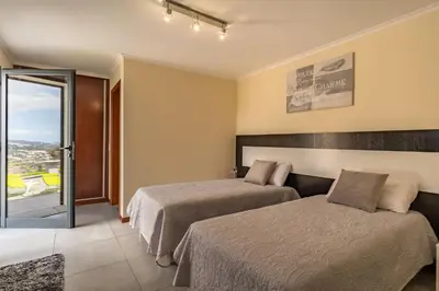a hotel room with two beds and a balcony at Gran Horizonte House by Holiday Rental Madeira in Ribeira Brava