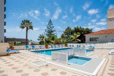 a swimming pool with blue chairs and a pool at Modern and cozy Apartment in Funchal