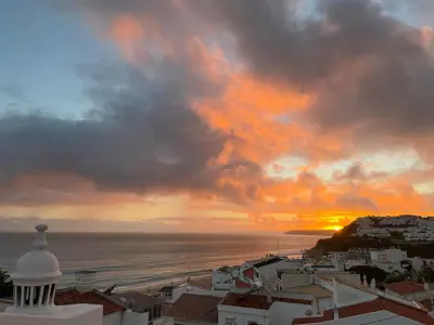 a sunset over a city with the ocean and buildings at Casa Pedro in Salema - Oceanview & beach in Salema