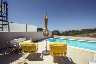 a patio with chairs and an umbrella and a swimming pool at 401 Villa Salemar in Salema