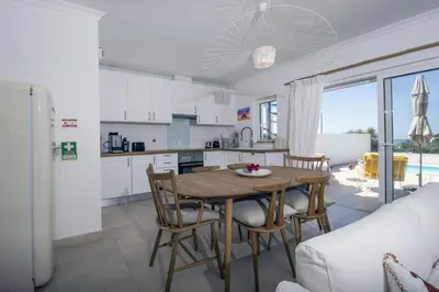 a kitchen and dining room with a table and chairs at 401 Villa Salemar in Salema