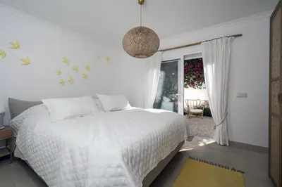 a white bedroom with a bed and a window at 401 Villa Salemar in Salema