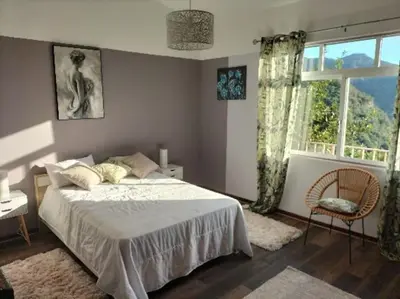 a bedroom with a bed and a chair and a window at Sea Mountain House in Machico