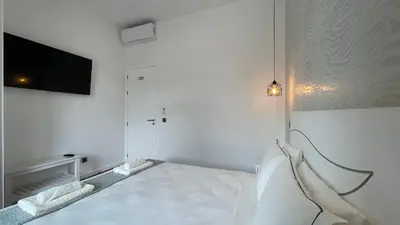 a white bedroom with a bed and a flat screen tv at Sea and Sun 4 You - Villa Oliveira in Funchal
