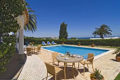 a patio with a table and chairs next to a swimming pool at Villa Camena, private pool, sea view, residential area outside of the village Praia da Luz in Luz