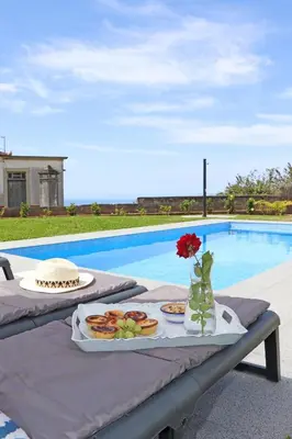 a house with a swimming pool in front of a mountain at Casa das Rosas e Casa Do Mar in Arco da Calheta
