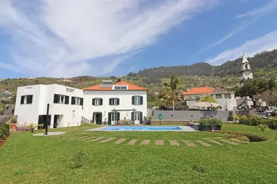 a white house with a swimming pool in a yard at Casa das Rosas e Casa Do Mar in Arco da Calheta