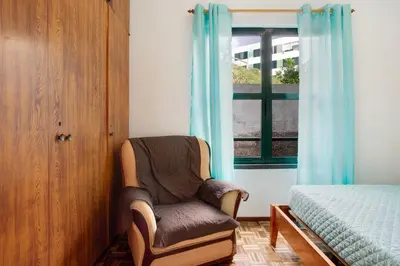 a chair in a room with a bed and a window at Slice of Paradise- Palheiro de Golf in Funchal