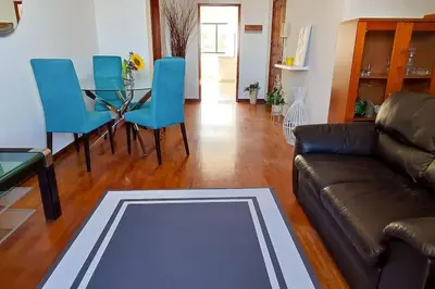 a living room with a couch and a table and blue chairs at Jardim Sol Holiday Apartment in Funchal