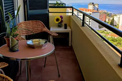 a small table and chair on a balcony at Jardim Sol Holiday Apartment in Funchal