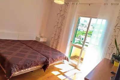 a bedroom with a bed and a sliding glass door at Jardim Sol Holiday Apartment in Funchal