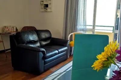a black leather chair in a living room with a table at Jardim Sol Holiday Apartment in Funchal