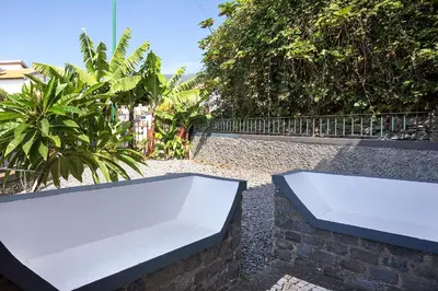a white bench sitting on top of a stone wall at Corman House, Sea View & Pool in Arco da Calheta