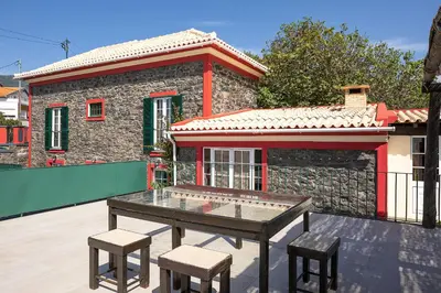 a table and two stools in front of a house at Corman House, Sea View & Pool in Arco da Calheta