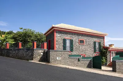 a small brick building with red accents on a street at Corman House, Sea View & Pool in Arco da Calheta