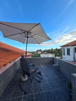 a patio with a chair and an umbrella on a roof at Casa dos Amigos Panoramic View in Funchal