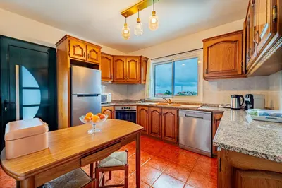 a kitchen with wooden cabinets and a wooden table at Casa Dolce Vita in Ponta do Sol
