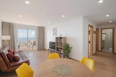 a living room with a table and yellow chairs at Garajau VI by An Island Apart in Santa Cruz