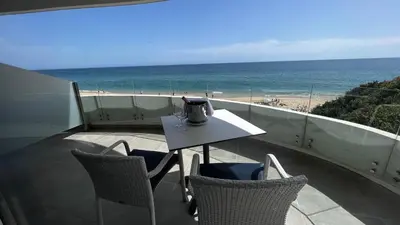 a table and chairs on a balcony with a view of the beach at Villamar in Salema