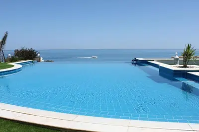 a large swimming pool with the ocean in the background at Breathtaking Villa with infinity pool over the sea in Luz