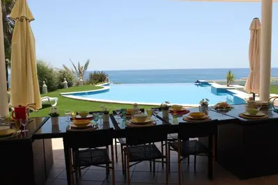 a dining table with chairs next to a swimming pool at Breathtaking Villa with infinity pool over the sea in Luz
