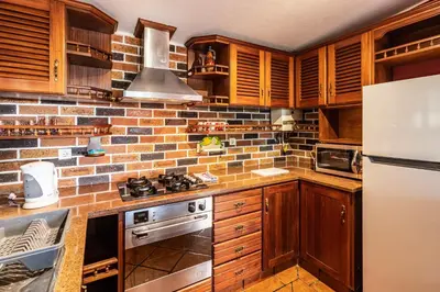 a kitchen with wooden cabinets and a brick wall at Cayenne House in Santa Cruz