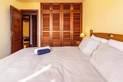 a large white bed with a blue pillow on it at Cayenne House in Santa Cruz