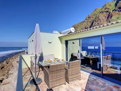 a house on the beach with an umbrella and a table at On the Wave by LovelyStay in Paul do Mar