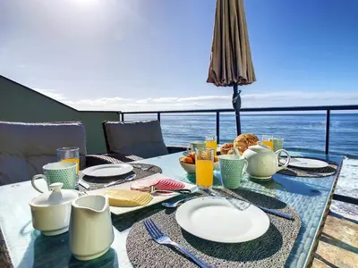 a table with plates of food and a view of the ocean at On the Wave by LovelyStay in Paul do Mar